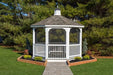 A full view of a white vinyl octagon gazebo with a gray shingle roof, surrounded by trees and landscaping.