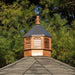 A wooden octagonal cupola with a bronze metal roof and decorative finial.