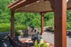 A wooden pergola with a fabric shade covering a patio with wicker furniture.